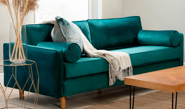Classic velvet teal couch with beige throw and white/teal scatter cushion in living room